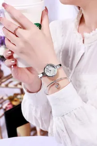 Silver glitter watch with sleek bracelet and heart pendant on a woman's wrist