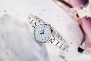 Close-up of JW silver steel watch with white dial and rhinestone on marble background