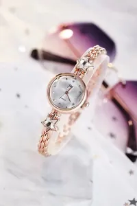 Detail of rose gold chain watch strap with sparkling crystal star charms and quartz dial