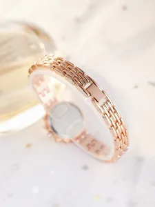 Detailed close-up of rose gold watch band with intricate metal chain mesh and buckle