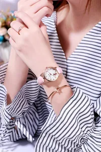 Nahaufnahme der rosa Katzenohr-Uhr mit Roségold-Sternarmband und offenem Ring am Handgelenk