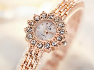Macro shot of rose gold flower-shaped watch dial with sparkling rhinestone petals