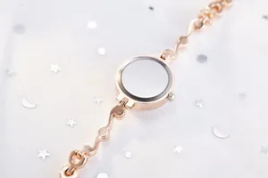 Détail d'une montre femme or rose avec bracelet à maillons en cœur et dos du boîtier