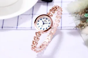 Détail d'une montre bijou en or rose avec de grands chiffres bleus sur cadran blanc