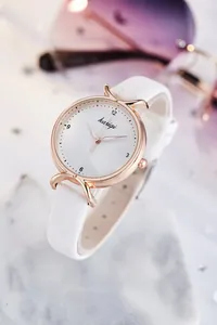 Gros plan d'une montre à quartz pour femme avec bracelet blanc et boîtier rose doré