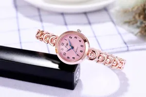 Détail d'une montre de mode rose doré avec cadran rose et bracelet chaîne évidé
