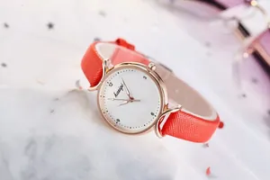 Gros plan d'une montre à quartz pour femme avec bracelet orange et boîtier en or rose