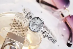 Silver chain strap ladies quartz watch with star charms and diamond dial on lifestyle background