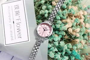 Detail of pink dial watch with rhinestone markers and polished silver steel band
