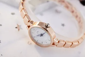 Detail of rose gold ladies watch with white dial and blue hands on white star fabric