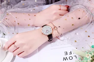 Close-up of rose gold starry dial watch with black leather strap and jewelry set