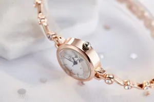 Détail d'une montre bracelet élégante en or rose sertie de cristaux sur du marbre