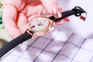 Detail einer roségoldenen Quarzuhr mit schwarzem Lederarmband und süßem Katzenmuster