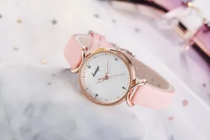 Détail d'une montre en cuir rose avec boîtier or rose sur tissu étoilé