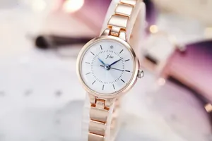 Detail of rose gold metal strap and white dial with blue hands on JW quartz watch