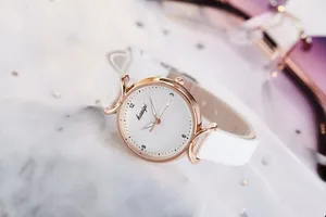 Gros plan sur une montre femme élégante en or rose avec bracelet et cadran blancs