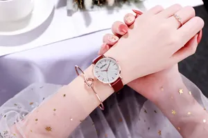 Elegant rose gold watch set with red strap, knot bracelet and ring on a female wrist