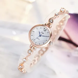 Élégante montre femme en or rose avec bracelet ondulé serti de cristaux sur fond marbre