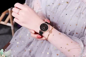 Primer plano del reloj de mujer cielo estrellado con correa de malla negra y cierre magnético