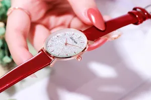 Close-up of sparkling starry silver dial and red leather strap on women's watch