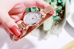 Primer plano de un reloj de oro rosa con esfera brillante y correa de malla metálica