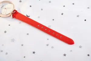 Détail d'une montre de mode pour femme avec bracelet en cuir rouge et boîtier en métal or rose