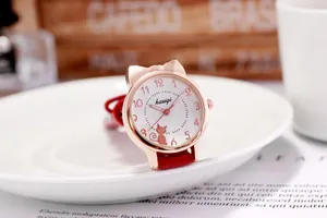 Nahaufnahme der roségoldenen Katzenohr-Quarzuhr mit rotem Lederarmband auf Tablett