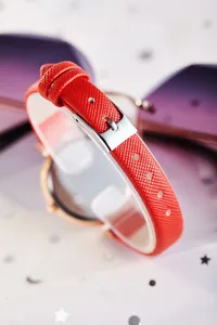 Détail du bracelet en cuir rouge grainé avec boîtier en or rose et boucle argentée