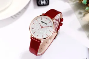 Detail of red leather strap watch with silver glitter starry dial and rose gold markers
