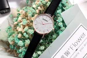 Detail of rose gold fashion watch with silver glitter dial and black leather strap