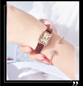 Detail of elegant rectangular gold watch with brown leather strap and heart bracelet