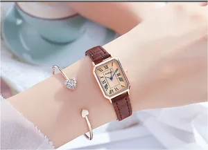 Close-up of elegant rose gold rectangular watch with brown leather strap and heart bracelet