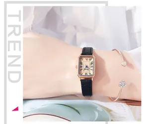 Close-up of rectangular rose gold quartz watch with black leather strap and heart bracelet