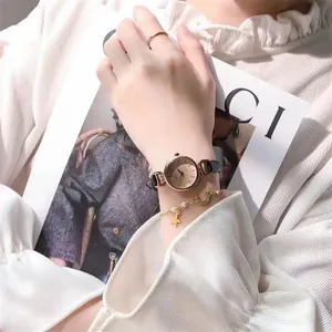 Detailansicht der goldenen Damenuhr und des Perlenarmbandes am Handgelenk einer Frau