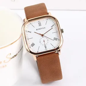 Close-up of a square rose gold quartz watch with a brown leather strap on a table