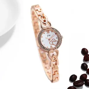 Detail einer roségoldenen Damenuhr mit herzförmigem Gliederarmband und weißem Zifferblatt