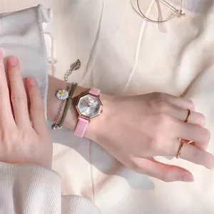Octagonal rose gold watch with pink leather strap shown on a wrist with accessories