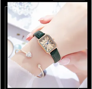 Close-up of retro rectangular gold watch with green leather strap and heart bracelet