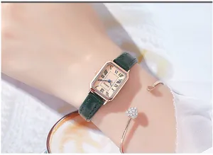 Detail of vintage rectangular quartz watch with green leather strap and gold heart bracelet