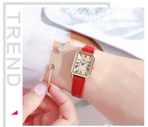 Close-up of elegant ladies' rectangular rose gold watch with red leather strap on wrist