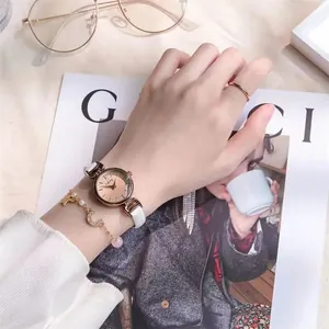 Nahaufnahme einer eleganten Golduhr mit weißem Lederarmband und Stern-Mond-Armbandset