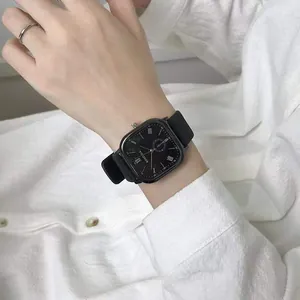 Minimalist black square quartz watch with Roman numerals and black strap on wrist