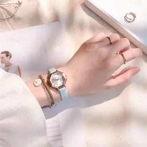Close-up of hexagonal rose gold watch with blue leather strap and daisy bracelet set