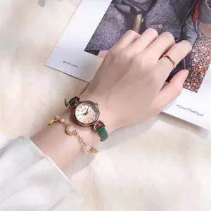 Nahaufnahme der goldenen Damenuhr mit grünem Lederarmband und passendem Armband-Set