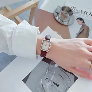 Detail van elegant rechthoekig roségouden horloge met bordeauxrode lederen band