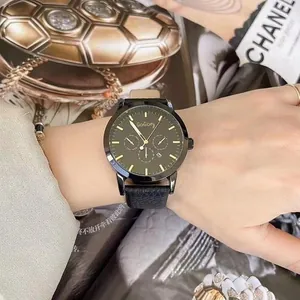 Detailed close-up of a black and gold fashion watch with sub-dials on a female wrist