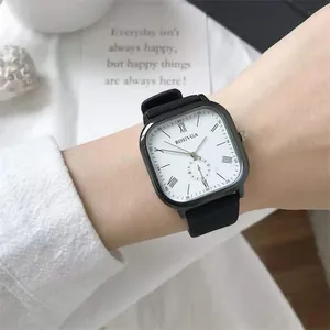 Minimalist square quartz watch with white dial and black strap on a person's wrist
