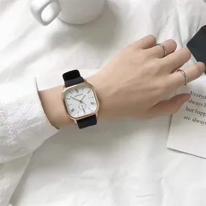 Close-up of square gold quartz watch with Roman numerals and black leather strap