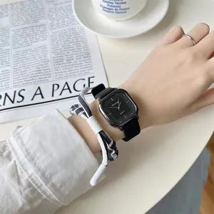 Minimalistische schwarze Quarzuhr mit gewebtem Armband am Handgelenk der Frau