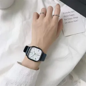 Minimalist square quartz watch with Roman numerals and navy blue matte strap on wrist
